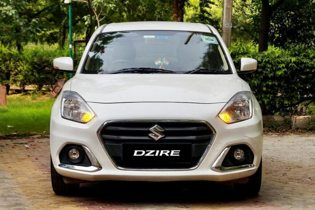 A white car parked in front of a lush green park